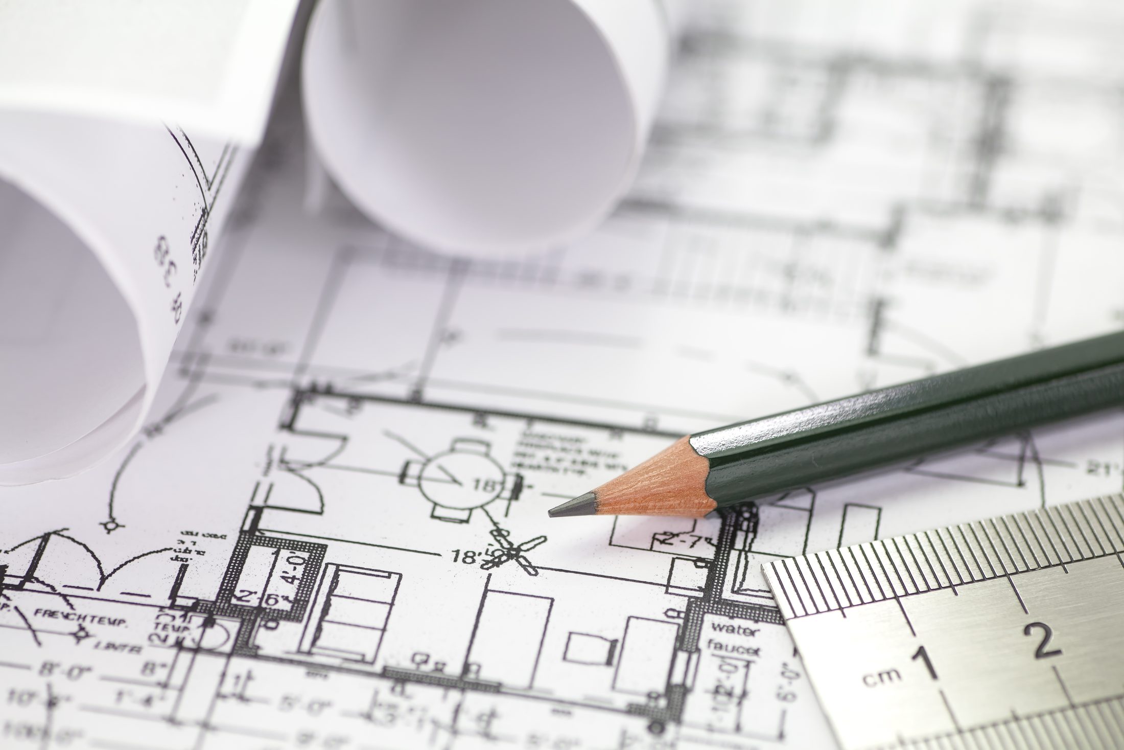 Bauplan mit Bleistift, Lineal und gerollten Plänen